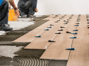 Workers applying tile planks to floor