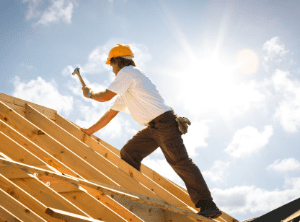 Roofer hammering nails into trusses of a roof