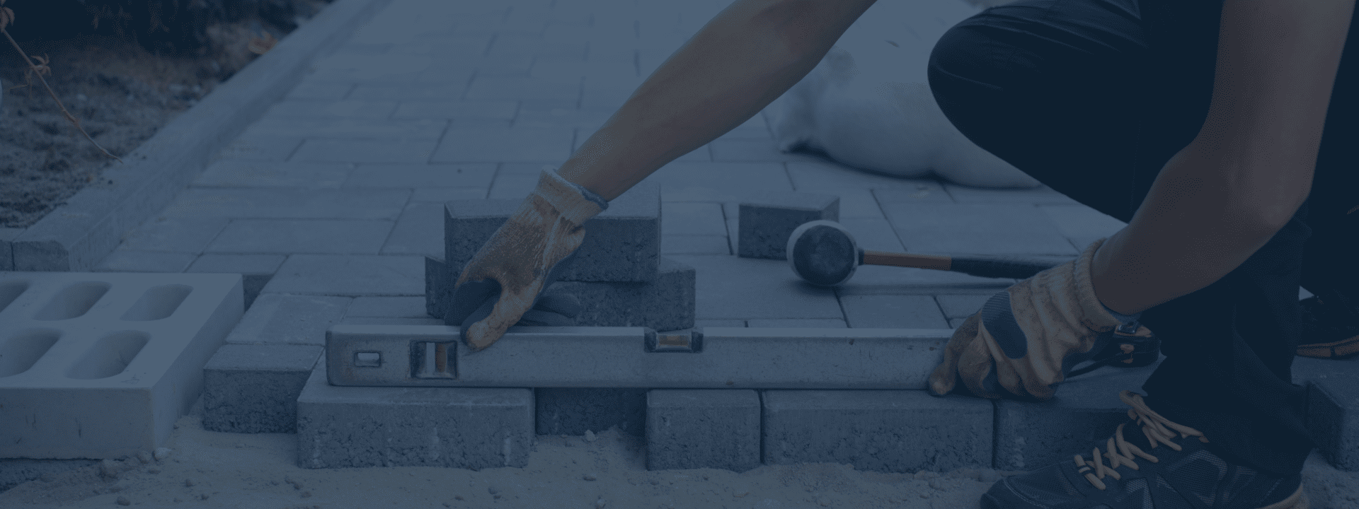 Concrete & Paving pro using a level on pavers