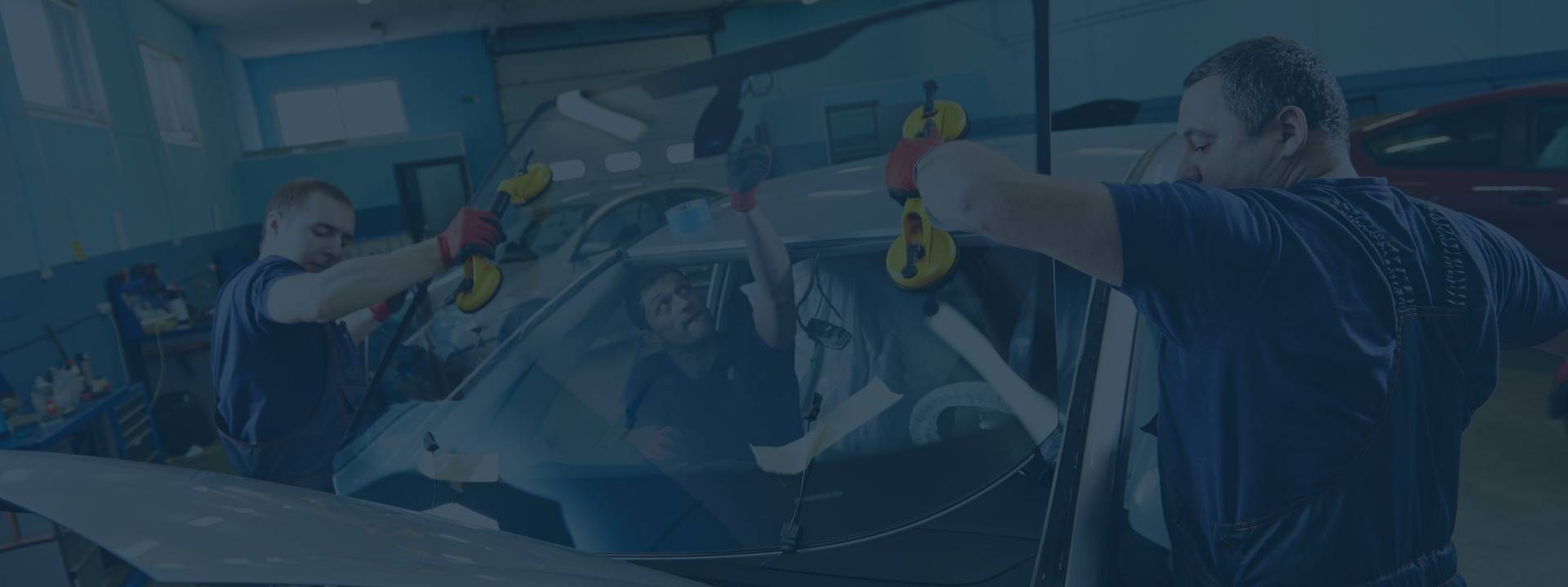 Auto glass technicians replacing windshield in an auto shop