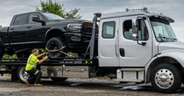 Towing professional securing a broken down truck onto a towing bed