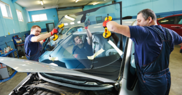 Auto glass professionals installing a new windshield on a car